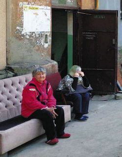 ウクライナ南東部マリウポリで4月27日、壊れた自宅アパート前に座るアルトゥールさんの母（左）＝アルトゥールさん提供